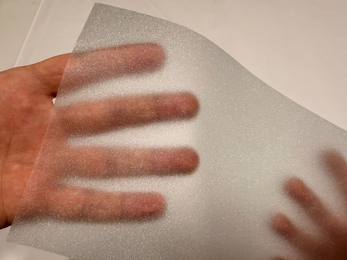 A hand behind a sheet of SHINECOR frosted film shows only as a blurred shape.